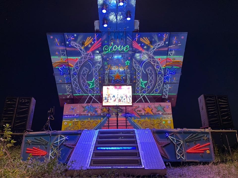 這張照片是一座大型的舞台,上面裝飾著許多彩色的燈光和圖案,像是星星、愛心和彩虹。舞台中央有一個巨大的螢幕,顯示著表演者的影像,舞台下方則有一條長長的階梯,通往舞台的中心。