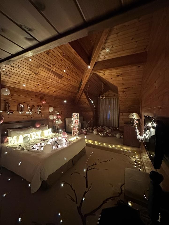 這張照片是一間佈置浪漫的房間,房間裡有床、氣球、燈光、以及一張小桌子,床上的氣球拼成“LOVE”字樣,非常溫馨浪漫。