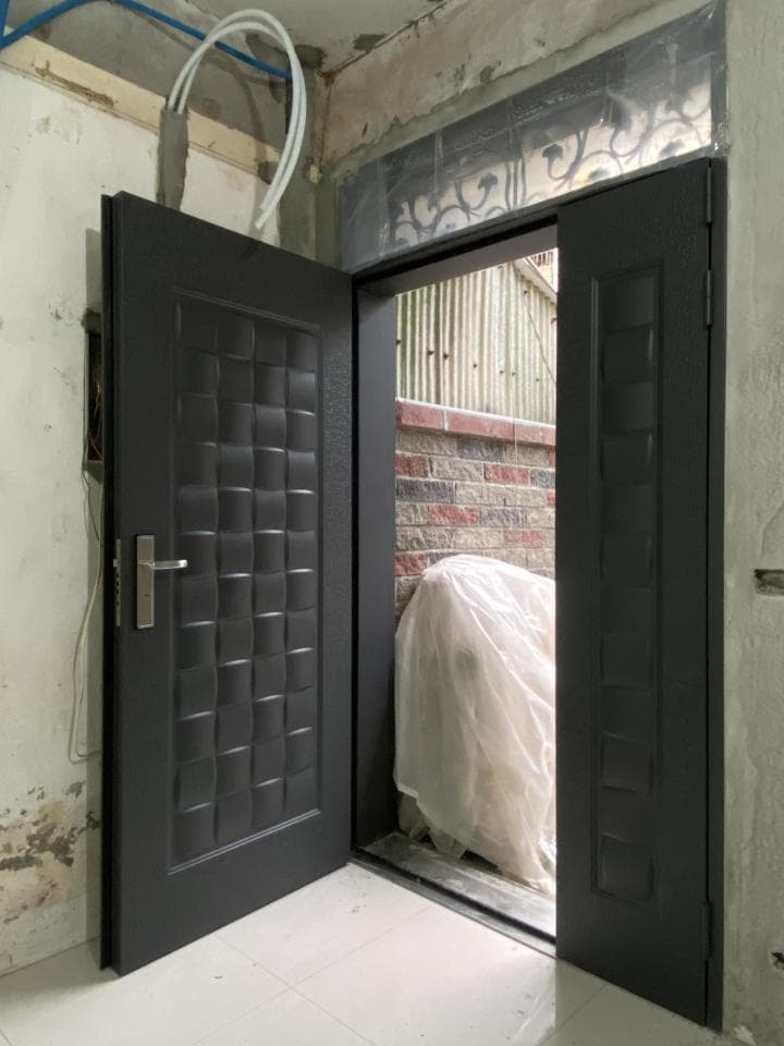 這張照片是一扇黑色金屬門,上面有格狀設計,門邊有白色的塑膠布。