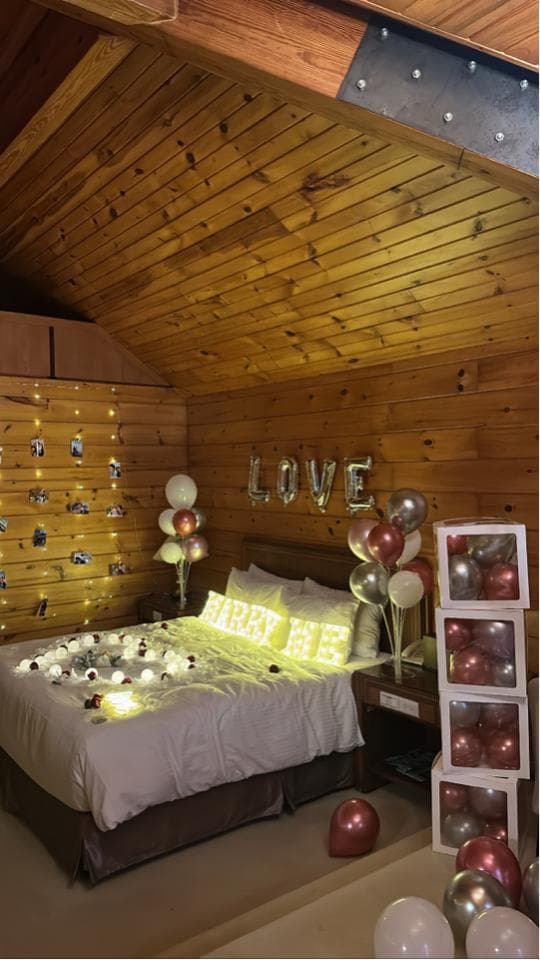 這張「佈置房間」的照片是木屋風格,房間裡有床、氣球、燈光和「LOVE」的裝飾。