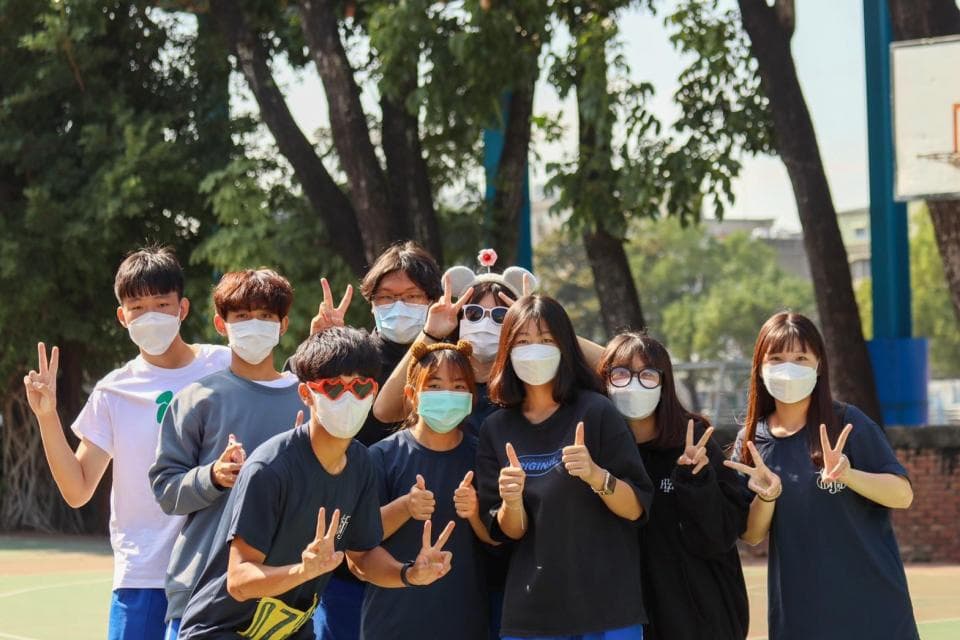 這張照片是一群戴著口罩的年輕人在戶外聚會,他們看起來很開心,彼此互動良好。