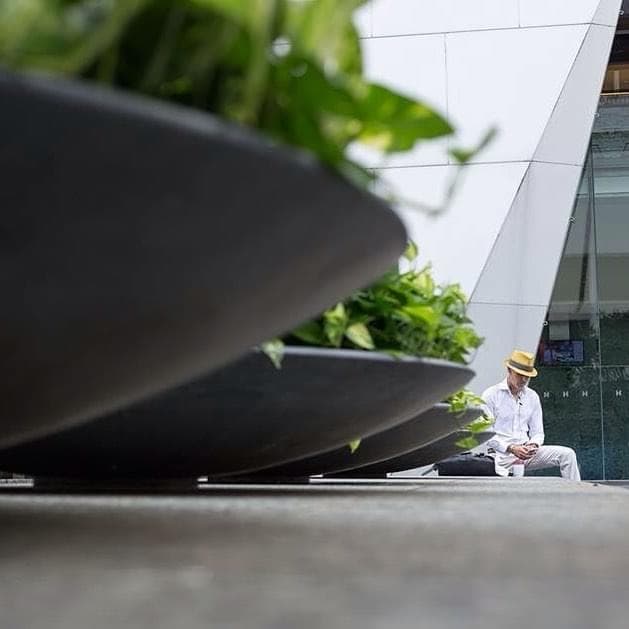 這張「幾盆植物放在建築物旁,一個男人戴著帽子坐在旁邊」的照片是。