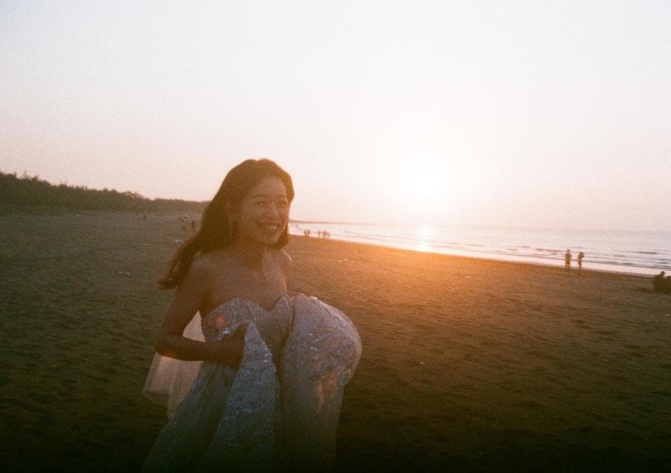 這張照片是一個穿著婚紗的女子站在海邊,背景是夕陽。