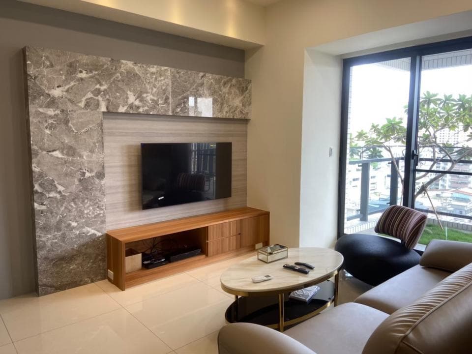 這張照片是客廳裡的一個電視牆,電視牆上貼著大理石磚,牆上有一台電視,電視下方有一個木製的電視櫃,電視櫃上放著一些裝飾品。