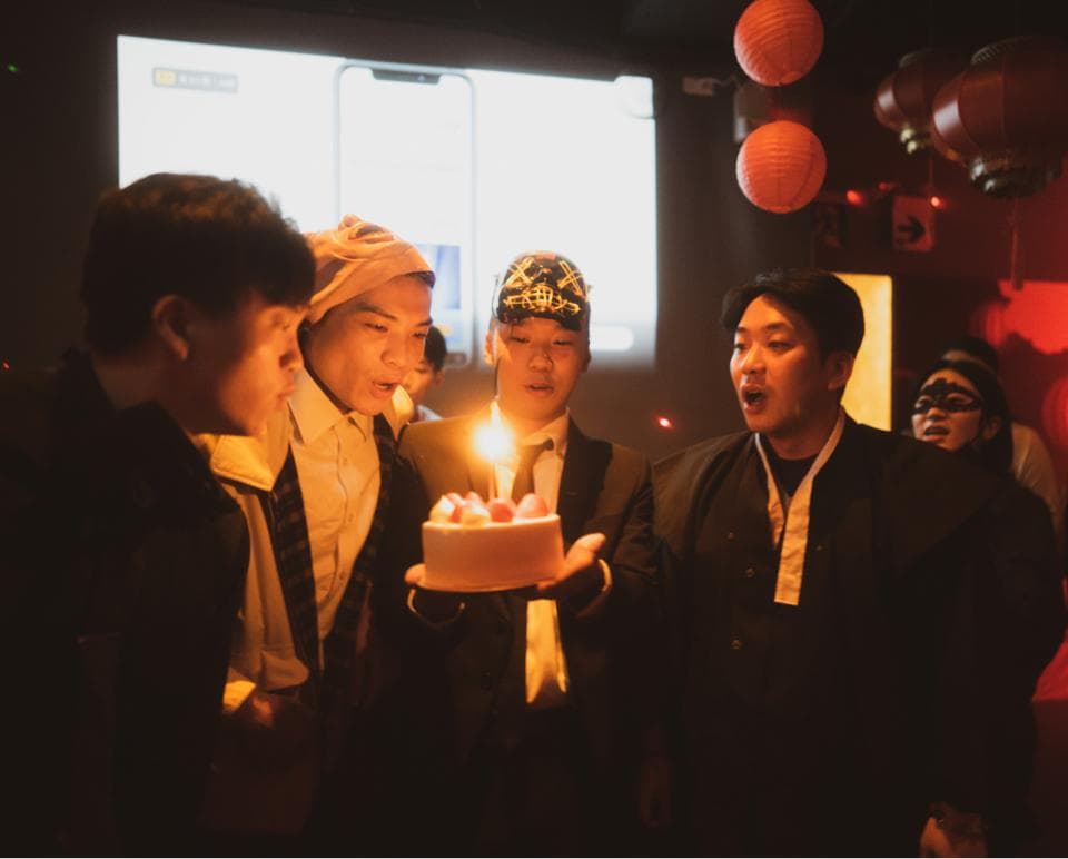 這張照片是一群朋友在慶祝生日,照片中最重要的部分是生日蛋糕,蛋糕上插著一根蠟燭,正在燃燒著。