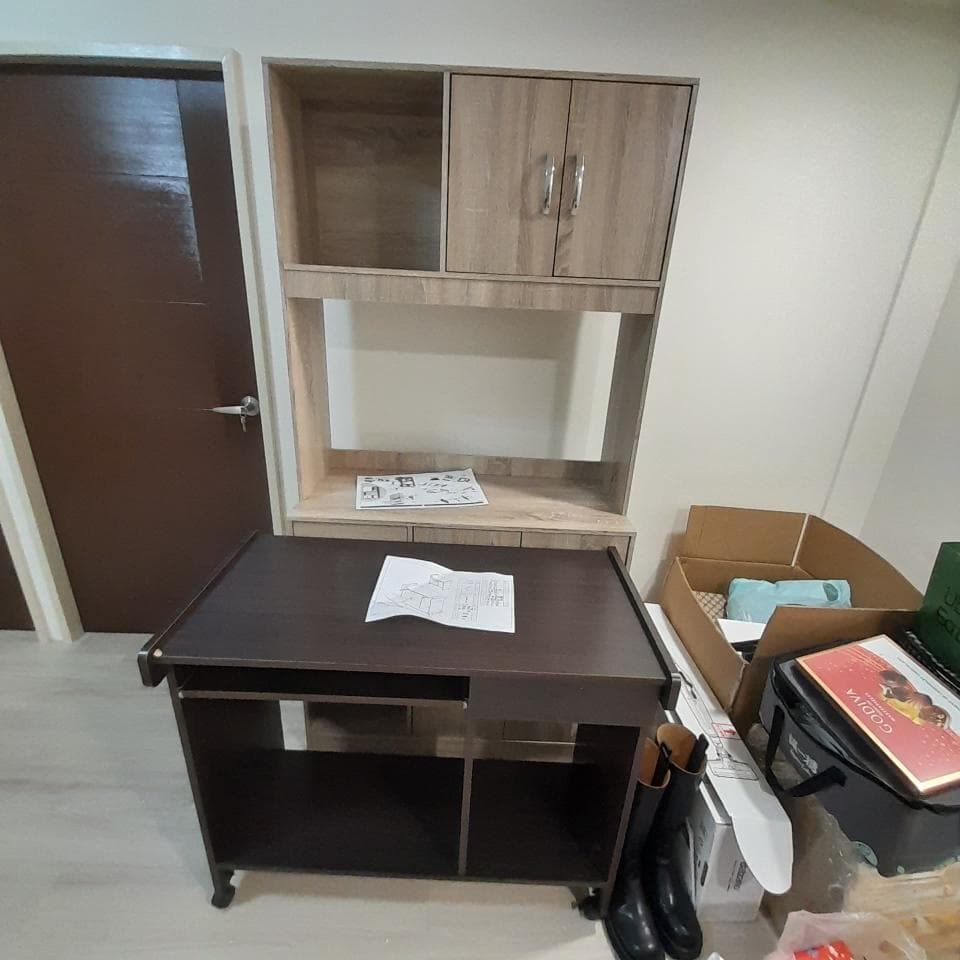 這張照片是一張木製的書桌,桌面上有張紙,書桌上方的櫃子裡放著一些物品。