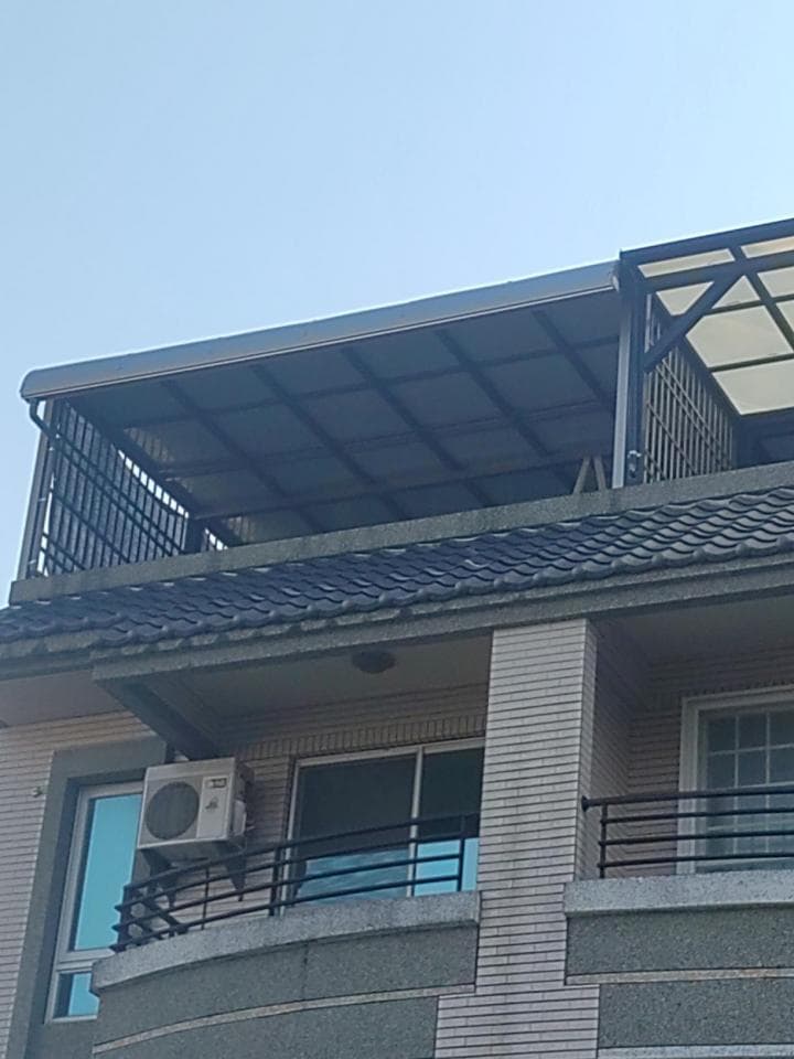 1) 照片顯示一棟房屋的陽台,陽台上有鐵製欄杆,並有一個白色遮雨棚