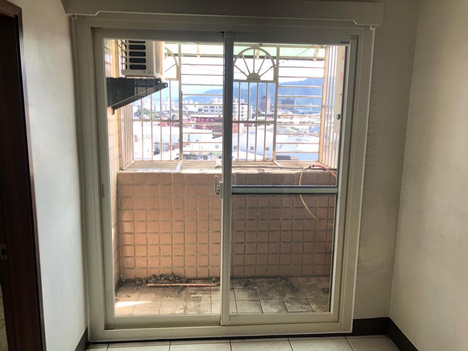 1) 照片顯示一個白色框架的窗戶,窗戶後面是一個陽台,陽台上有瓷磚地板和一個鐵製的欄杆