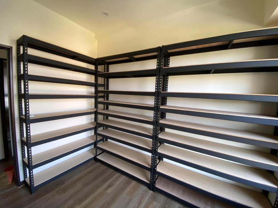 這張照片是一間房間裡,有兩個大型黑色金屬層架,上面放著木板。