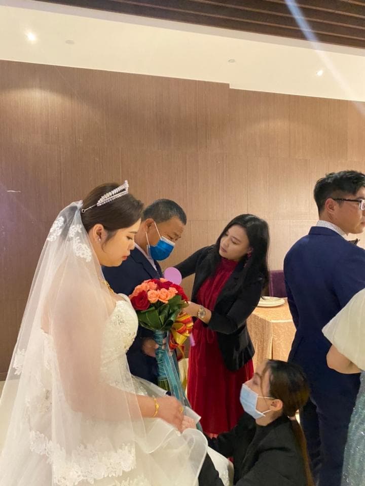 這張照片是一對新人結婚的場景,新娘穿著白紗,新郎穿著西裝,他們正在接受親朋好友的祝福,現場充滿喜悅和幸福的氣氛。