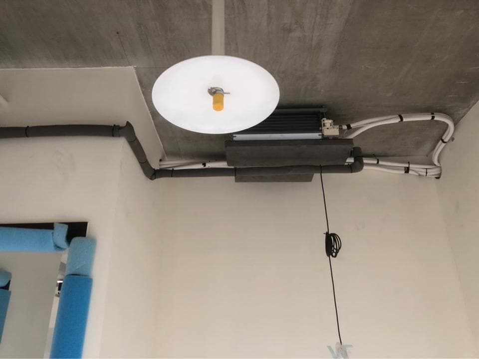 這張照片是一個安裝在房間天花板上的空調系統。空調系統的室外機被安裝在牆壁上,並連接著許多管線。