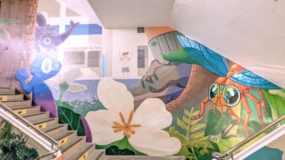 這張照片是一幅牆上的壁畫,牆上畫著一隻巨大的橙色蜻蜓,蜻蜓有著明亮的綠色眼睛和藍色的翅膀,旁邊有一朵白色花朵,花朵的中心是黃色的。