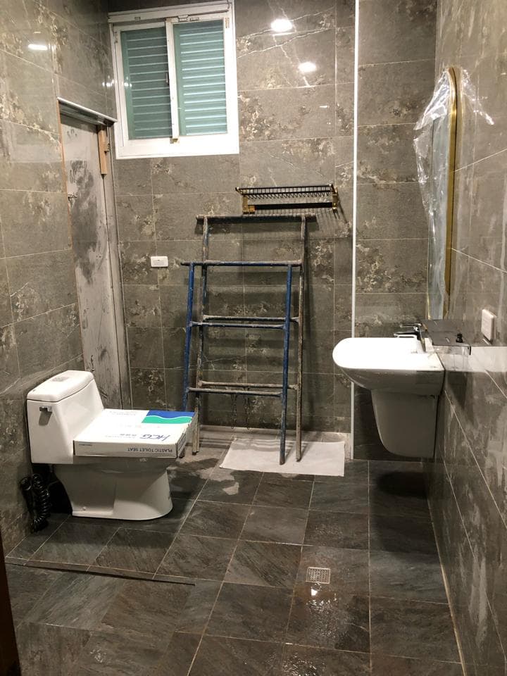 1) 這是一張浴室的照片,裡面有一台馬桶、一個洗臉盆、一個梯子、一個窗戶、一個鏡子和一些灰色的磁磚