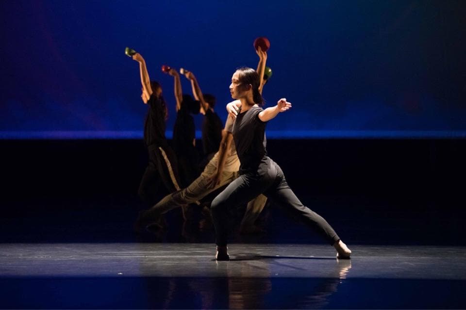 1) 照片顯示一群穿著黑色衣服的舞者在舞台上表演