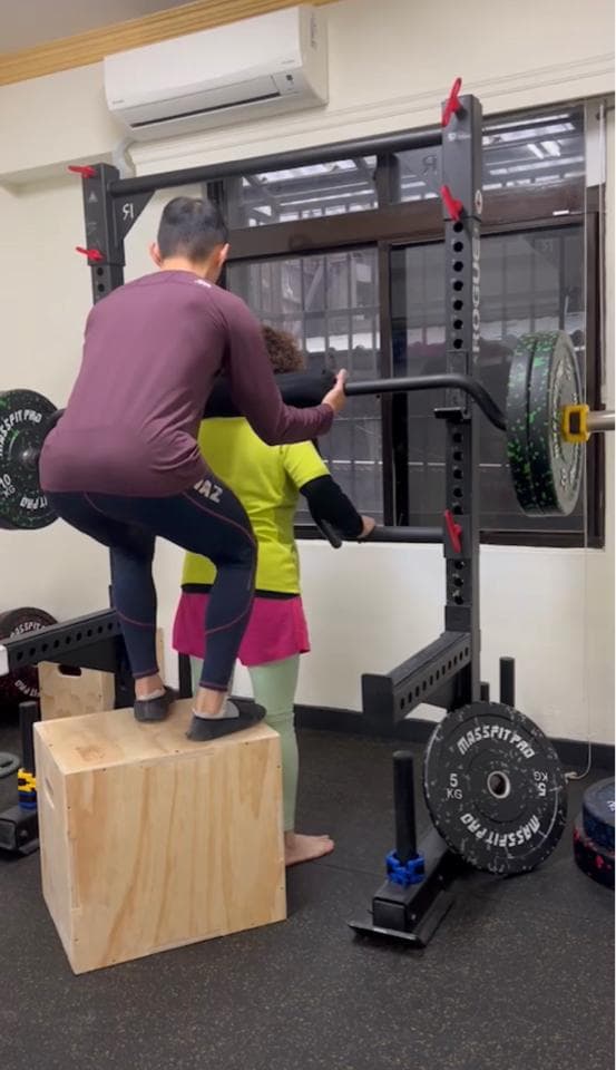 這張照片是一個健身房,照片中最重要的部分是一個木箱。木箱是由淺色的木頭製成的,四四方方,上面有一個男生站著。