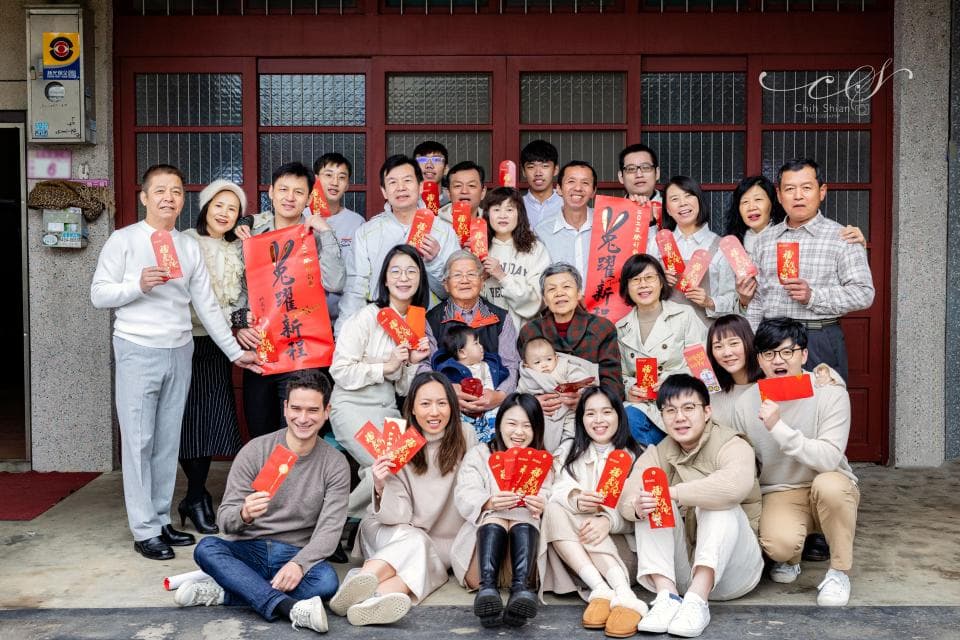 這張照片是一家人在門前拍的合照,照片中每個人都面帶微笑,看起來非常溫馨和樂。