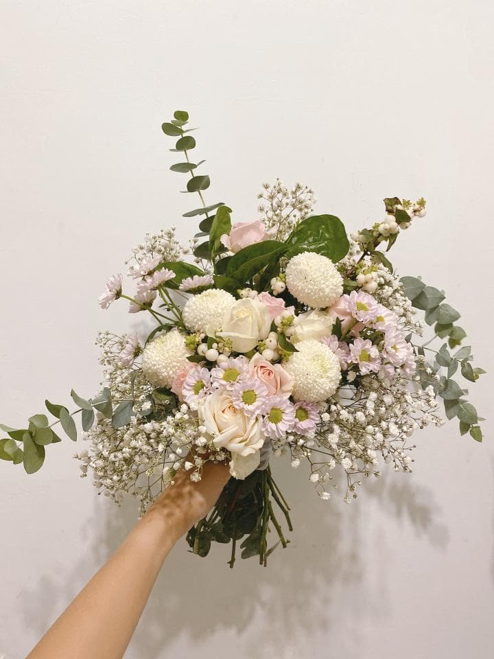 這張「花束」的照片是 一束由白色和粉色花朵組成的花束,其中包含一些綠色的枝葉。