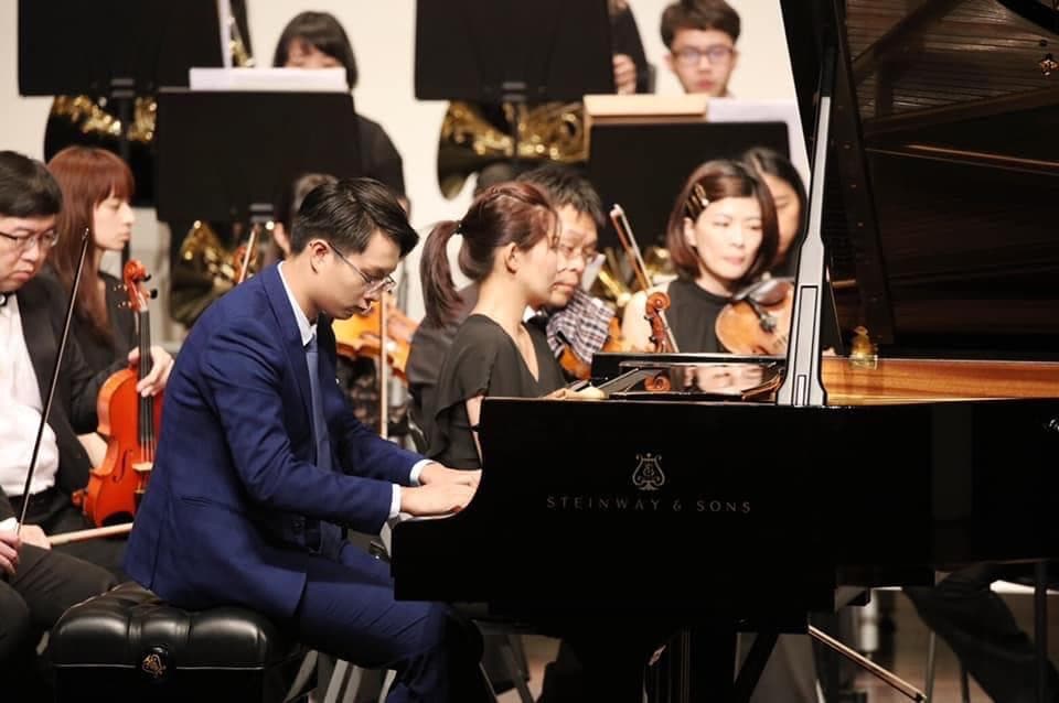 這張照片是一個鋼琴演奏會,最重要的部分是演奏者正在彈奏一架黑色鋼琴,鋼琴上寫著 Steinway & Sons。