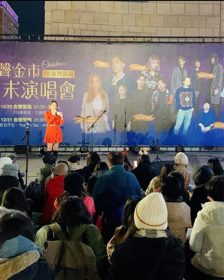 這張照片是聖誕節期間舉辦的音樂會,照片中最重要的地方是舞臺中央正在唱歌的女生。她穿著紅色短裙和外套,手持麥克風,正在投入地演唱。