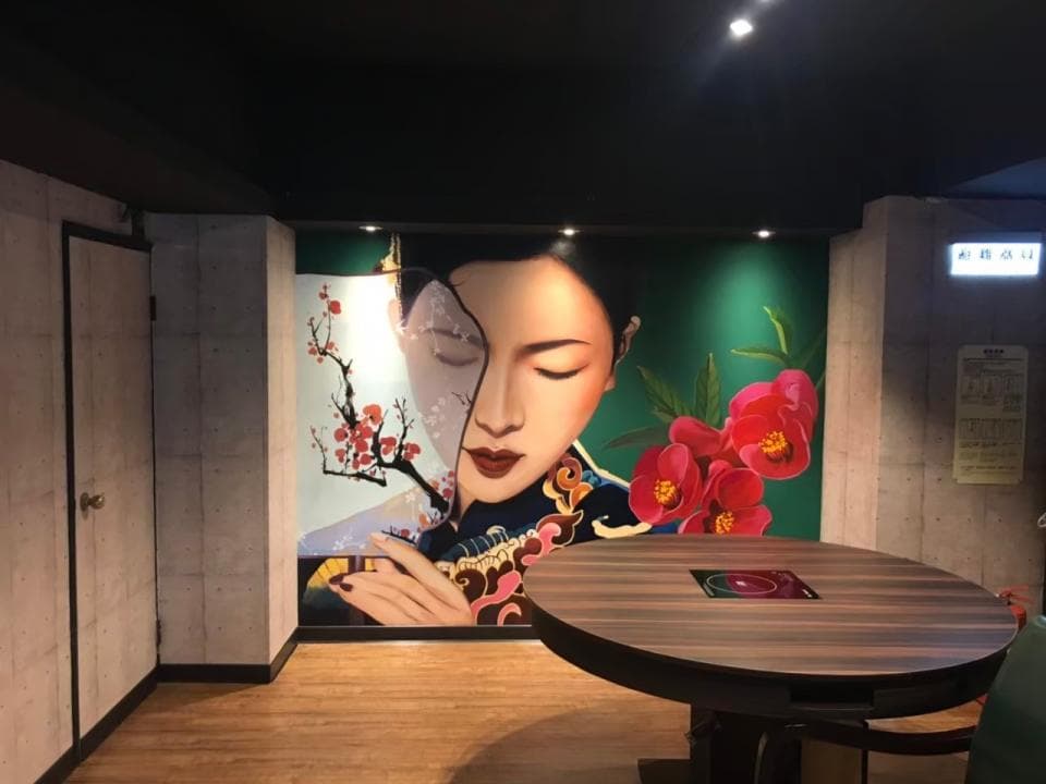 這張「餐廳內部」的照片是一間裝潢精緻的餐廳,牆壁上有一幅美麗的壁畫,圖案是一個中國女人,旁邊有花朵,餐廳裡有一張圓桌和椅子,適合朋友聚餐。