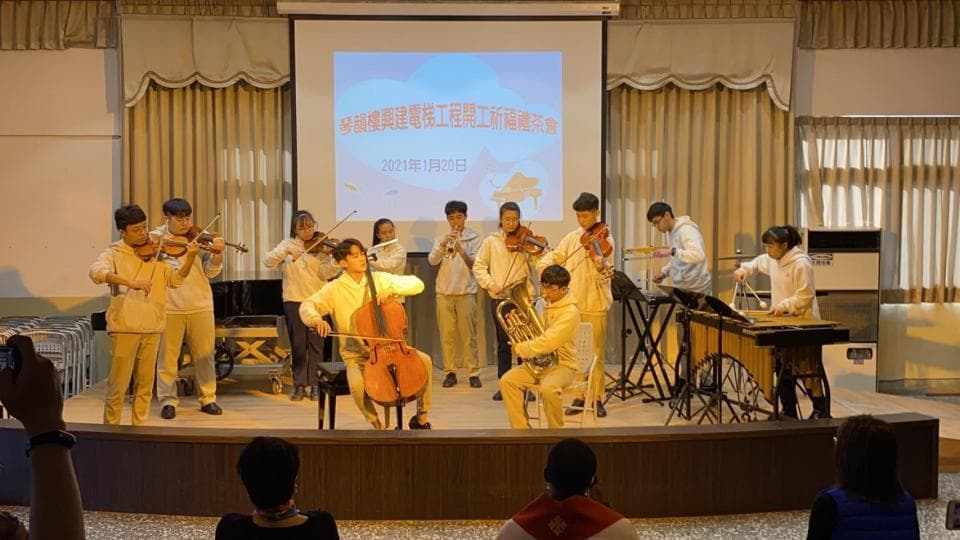 這張照片是一群學生在舞臺上表演音樂,最顯眼的是一位學生正在演奏大提琴,他專注的神情和精湛的技巧讓人印象深刻。