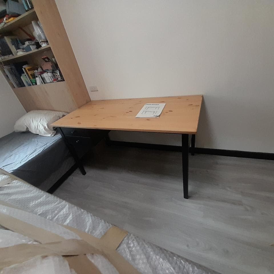 1) 照片顯示一個木質書桌,桌面是淺色的木頭,桌腳是黑色的鐵製