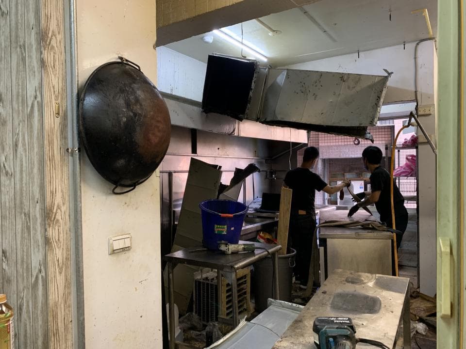 這張「廚房」的照片是兩個工人正在拆卸舊的抽油煙機。