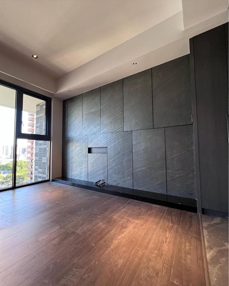 這張照片是一間現代化的客廳,最重要的是客廳的木地板,呈現出溫暖舒適的氛圍。地板採用深色木紋,搭配深灰色的牆面,營造出沉穩大氣的空間感。