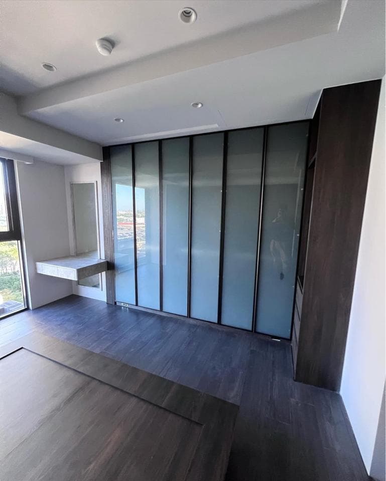 這張照片是一間現代化的臥室,最重要的是房間的整體設計,包括木質地板、簡約的衣櫃以及採光充足的窗戶。