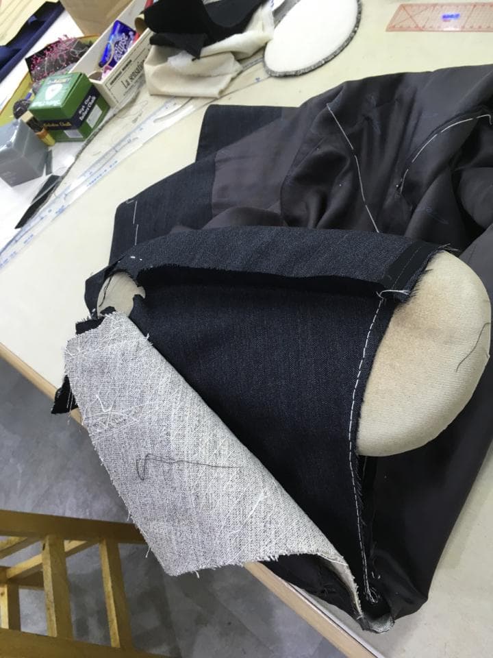 這張照片是一個縫製的布料,主要部分是一塊灰色的布料,正在被縫到一塊黑色的布料上。