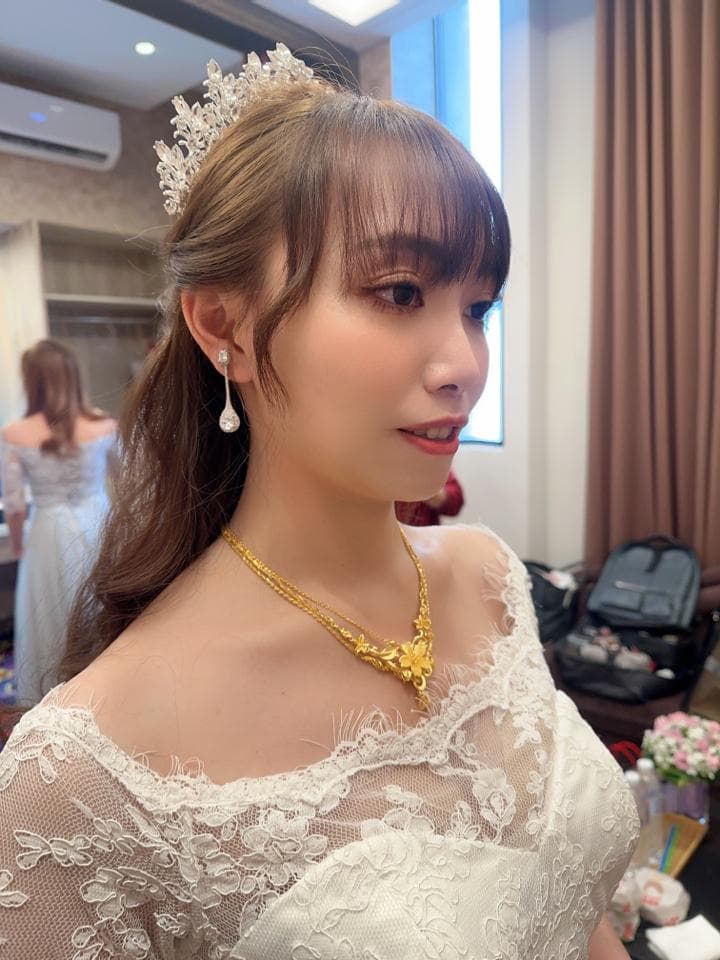 這張婚紗照是一位戴著皇冠,穿著蕾絲婚紗的女性,她手裡拿著一個捧花。