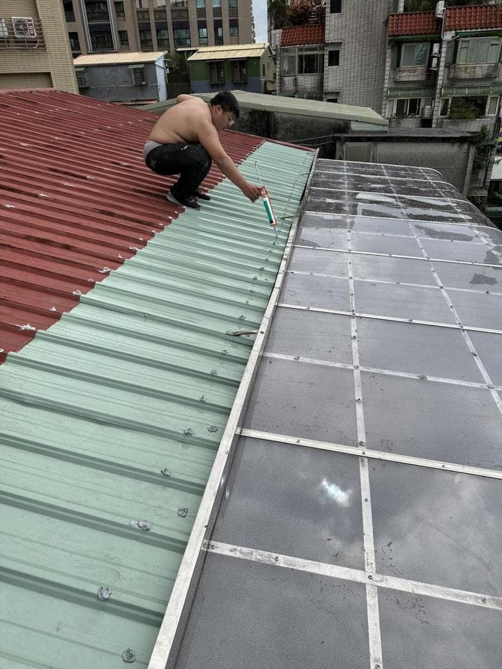 1) 照片顯示一名男子站在屋頂上,他正在修理一個金屬天窗