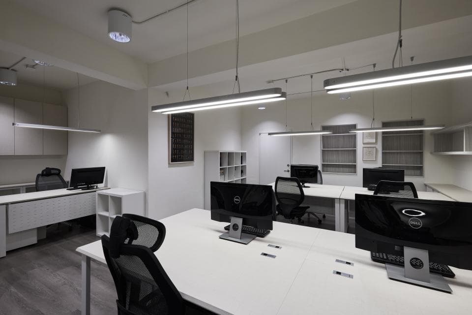 這張「辦公室」的照片是一間簡潔明亮的辦公室,有白牆、白色桌子和黑色電腦,營造出清爽的辦公環境。