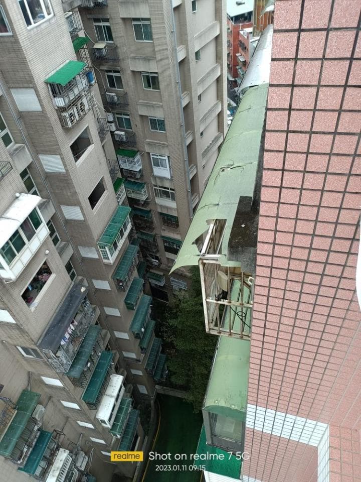 這張照片是兩棟大樓之間的狹窄空間,其中一棟大樓的牆壁剝落,露出裡面的鐵架結構。