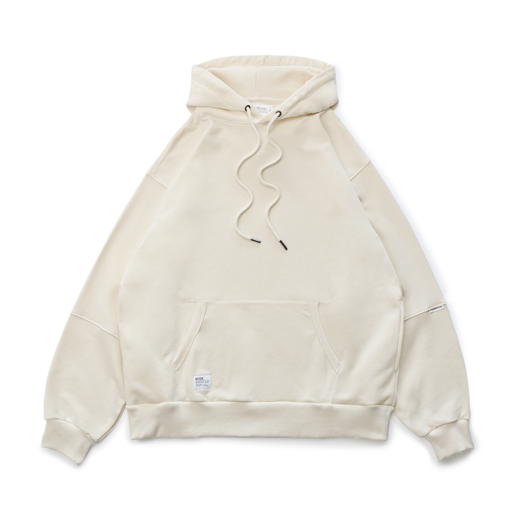 這張照片是一件米白色的連帽外套,它有寬鬆的版型,並有一個大口袋。外套的帽子上有黑色的抽繩,設計簡潔大方。