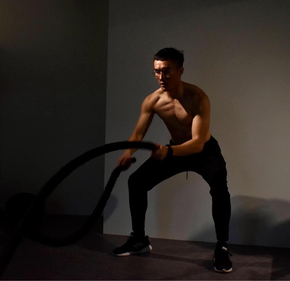 這張照片是一個男人在健身房裡鍛鍊,他正在使用一根繩索進行運動,他的動作很用力,他看起來很專注,這表明他是一個非常認真的人。