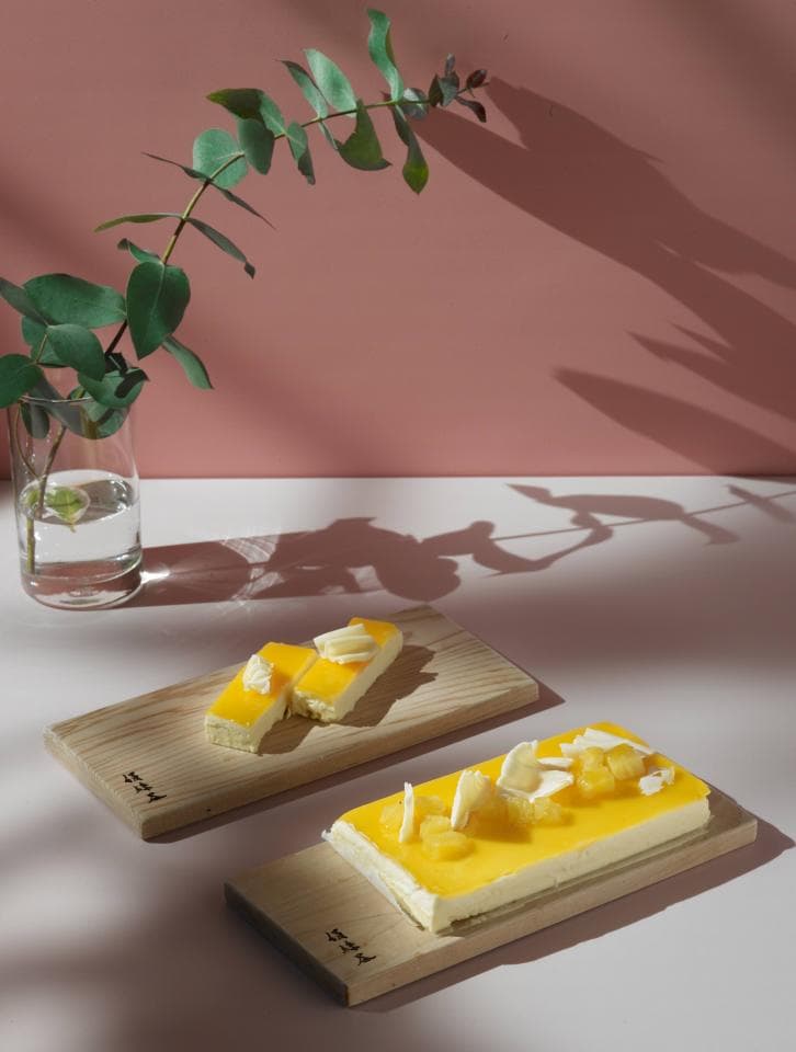 這張「甜點」的照片是兩塊木板上放著兩塊檸檬蛋糕,蛋糕上分別擺著一塊白色巧克力和一些菠蘿塊。