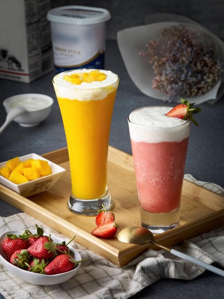 這張「飲品」的照片是兩杯飲料,一杯黃色,一杯紅色,旁邊有芒果和草莓。