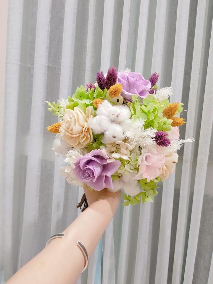 這張「婚禮花束」的照片是一束以紫色和白色為主色調的乾燥花束,花束中包含玫瑰、滿天星、棉花等花卉,並以緞帶裝飾。