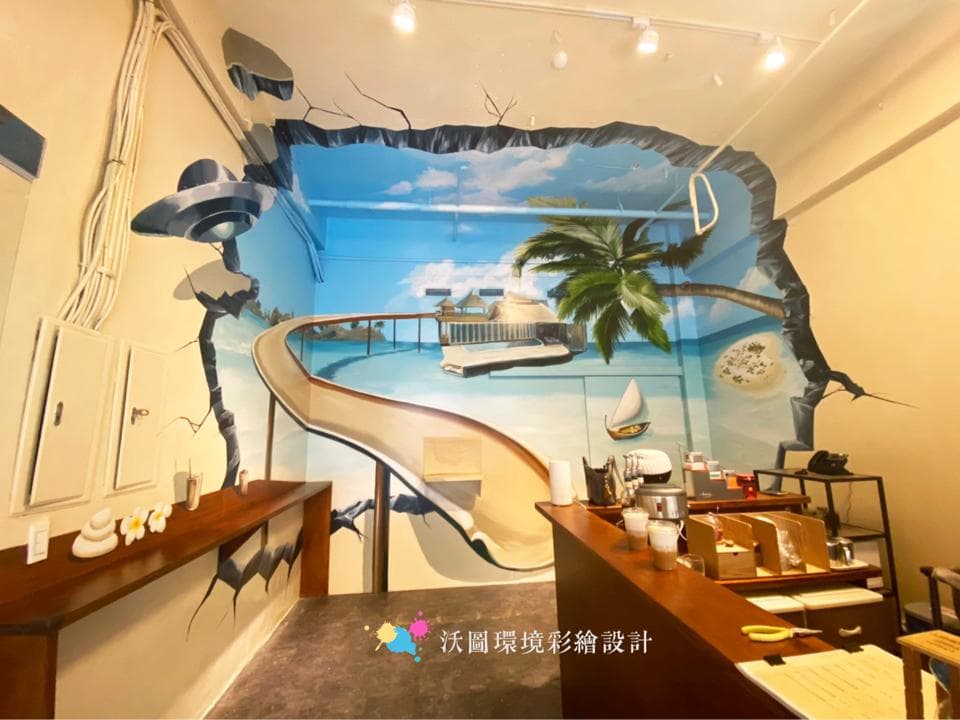 這張照片是一個有壁畫的房間,壁畫看起來像一個海灘,牆壁上有一個滑梯,看起來可以滑到海灘上。