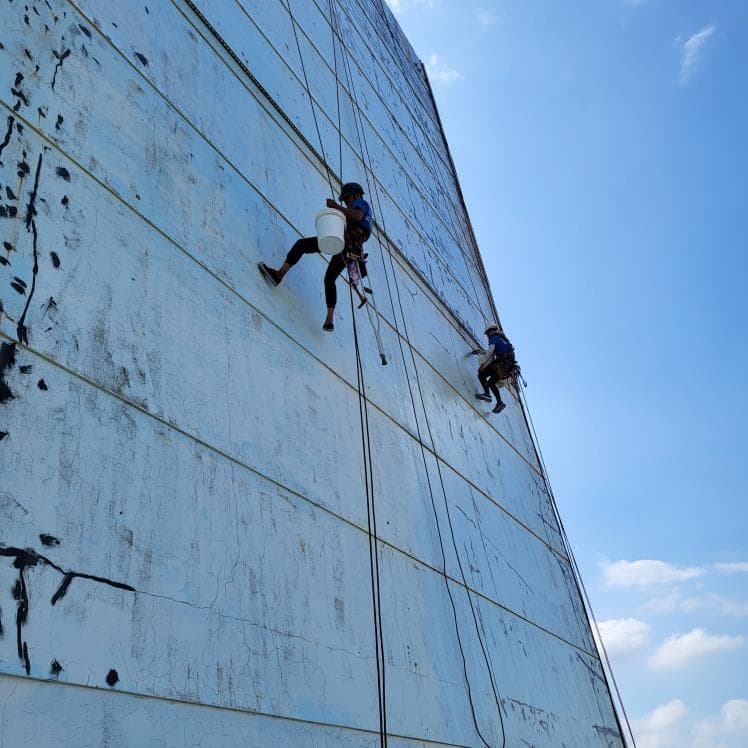 1) 這是一張照片,拍攝了兩個人懸掛在高樓外牆上,進行清洗或維修工作
