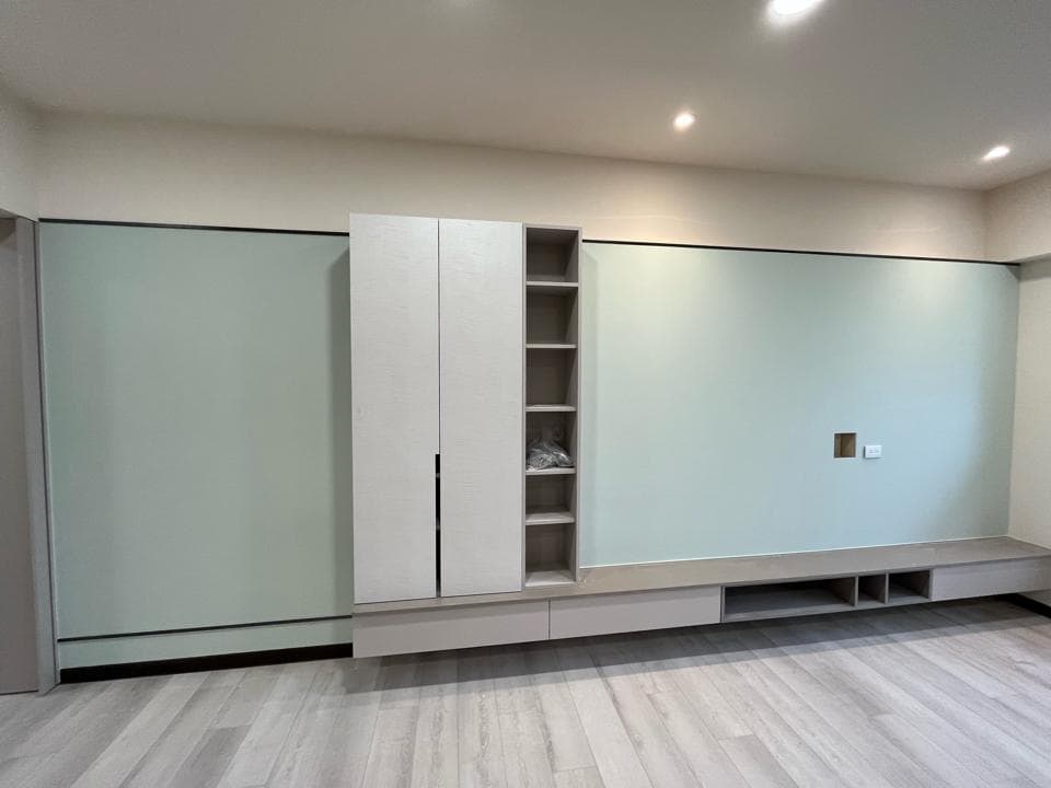 1) 照片顯示一個現代的客廳,其中有一組白色的儲物櫃和一個嵌入式的電視櫃,櫃體下方是一個淺灰色的平台