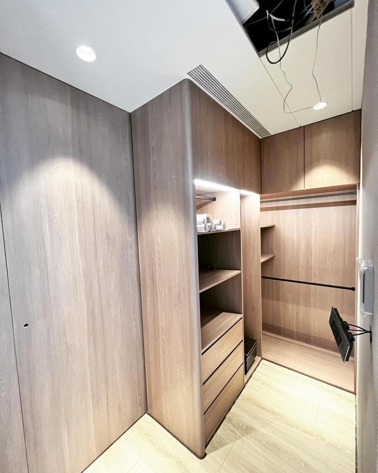 1) 照片顯示一個現代化的臥室衣櫃,衣櫃有木質門板和抽屜,並有燈光照明