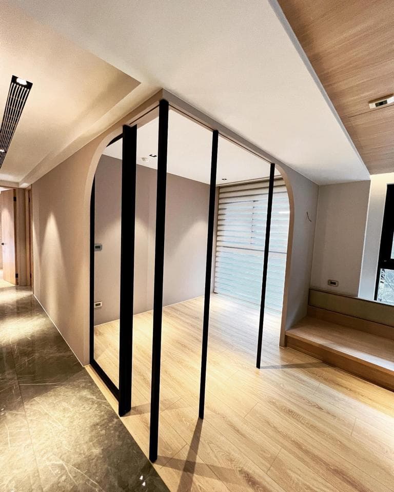 這張照片是一間現代風格的房間,房間內設計了一個以黑色框架構成的拱形門,將空間分隔成兩個區域,增加了空間的層次感。