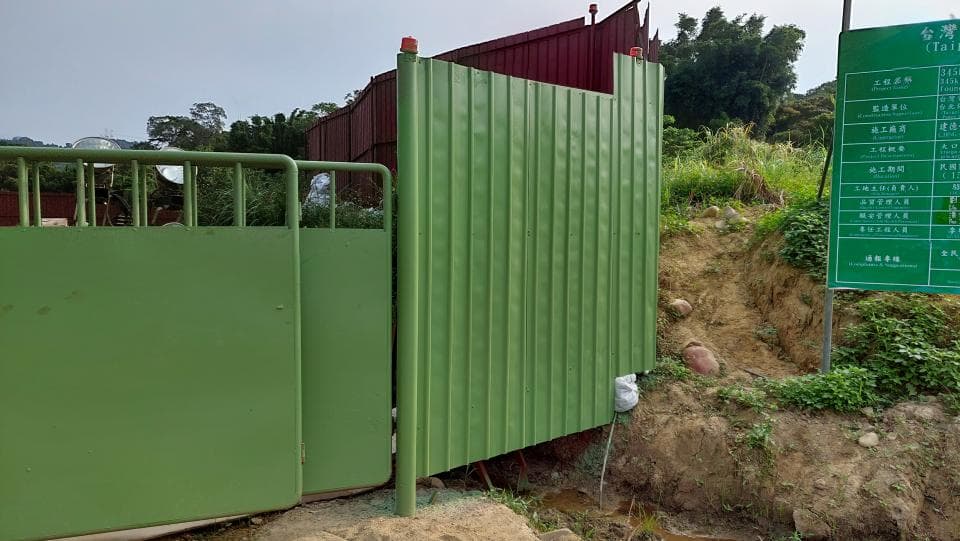 這張照片是一堵綠色的金屬圍欄,它被用作建築工地的圍牆。圍欄上有一些豎直的條紋,它看起來很堅固。