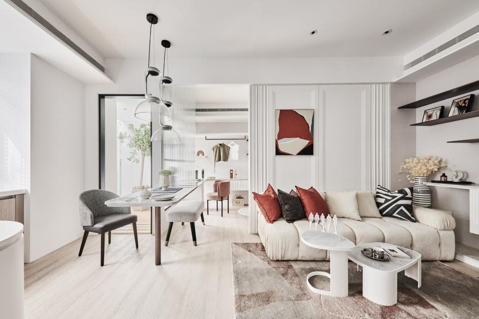 這張照片是一間現代風格的客廳,照片的重點是客廳裡面的白色沙發。沙發上擺放了多個抱枕,並且配有兩張白色的茶几。