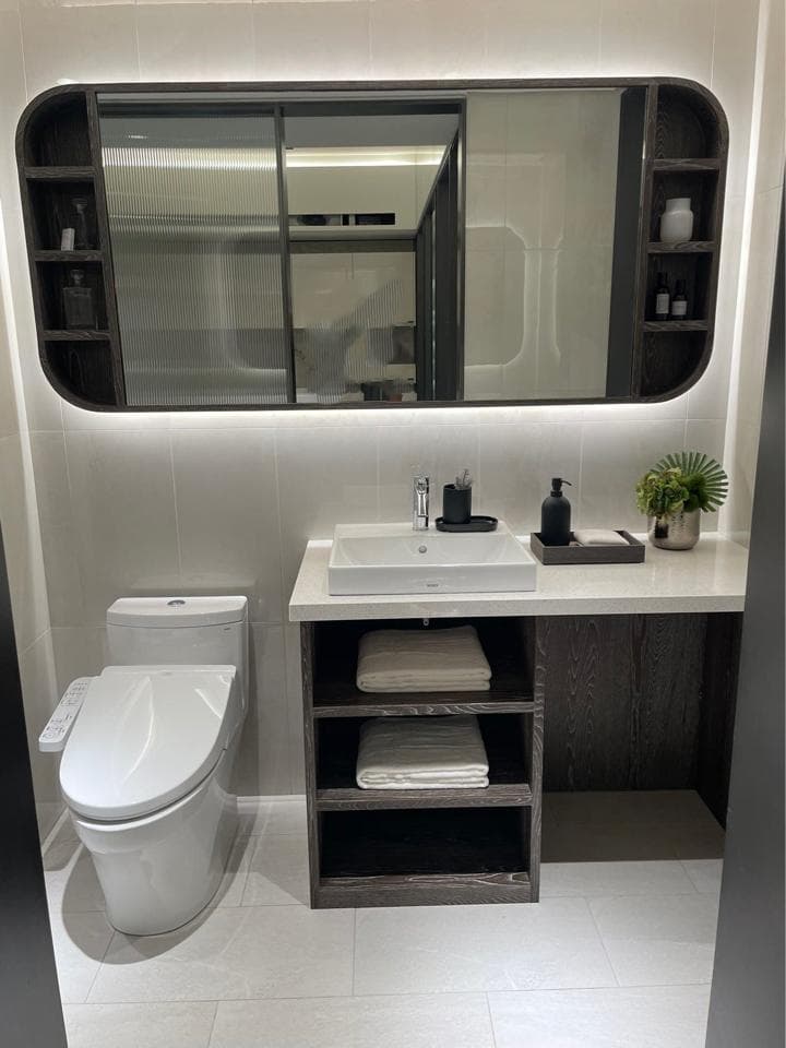 這張照片是一間現代化的浴室,最重要的是浴室的洗漱台。洗漱台配備了白色陶瓷洗手盆,下方設有兩個層架,上面放了毛巾,下方則有一個抽屜櫃,可供存放洗漱用品。