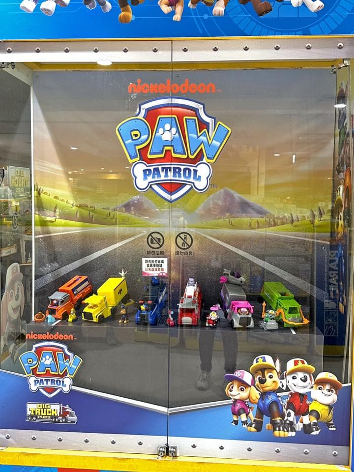 這張照片是一間玩具店,最重要的是櫥窗裡展示的「汪汪隊」玩具,其中包含了多輛「汪汪隊」成員的車輛,還有「汪汪隊」的標誌。
