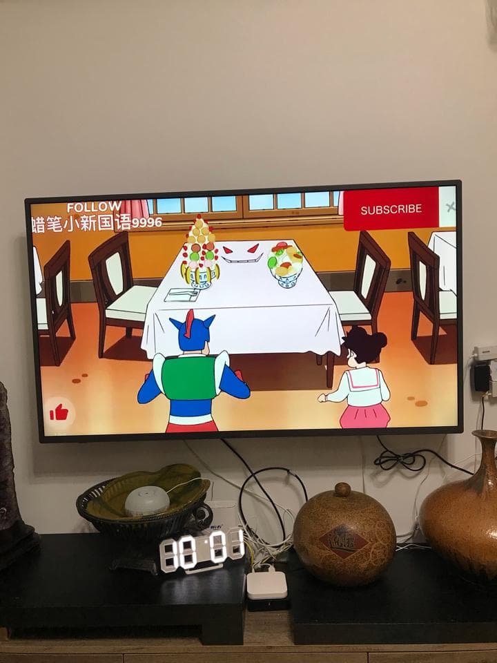 這張照片是電視螢幕上播放的卡通節目,畫面上出現了兩個卡通人物,一個穿著藍色制服,一個穿著白色連衣裙,他們正圍繞著一張桌子。