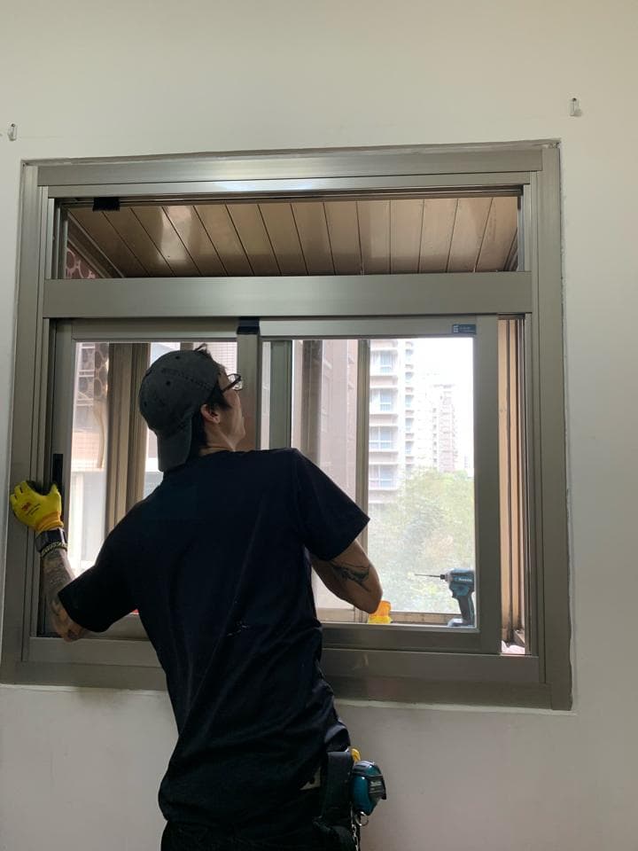 1) 照片顯示一名身穿黑色 T 恤和棒球帽的男子正在安裝窗戶